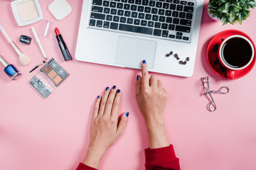 Woman hands using laptop computer on pink desk table,Top view,Flat lay.