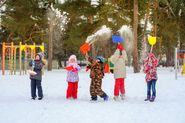 children play in the winter park, throw snow and have fun