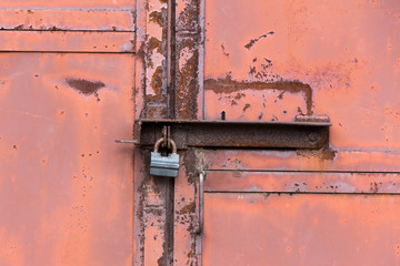 rusty metal door closed on the padlock. old metal texture