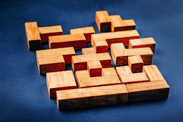 Different geometric shapes wooden blocks on a dark background. Creative, logical thinking and problem solving concept