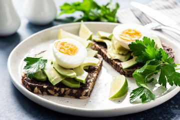 Toast with avocado and boiled egg on a plate, closeup view. Healthy breakfast, healthy eating or snack concept