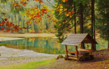 Lake in a forest with a gazebo and small pier for pleasure pedal catamaran on the lake shore.