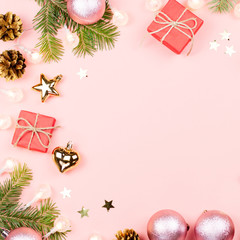 Christmas background with fir branches, lights, red giftboxes, pink decorations, hot drink with marshmallows on pink