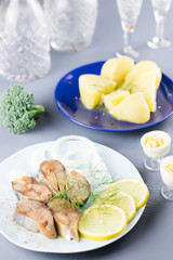 Sliced salted fish with lemon and seasoning, boiled potatoes on a table