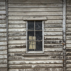 Fototapeta na wymiar Isolated, partial view of old weathered grey wooden barn with paned windows