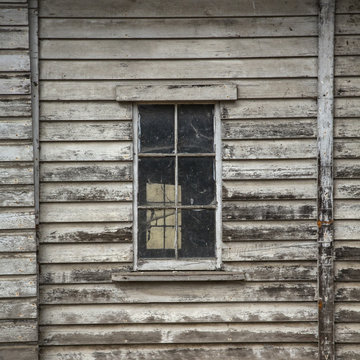 Isolated, partial view of old weathered grey wooden barn with paned windows