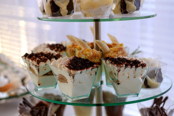 Delicious tasty tiramisu cakes, in a glass bowl, on a glass stand in a restaurant. Selective focus.