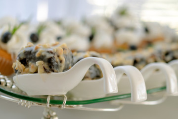 Delicious tasty cakes, in ceramic decorative spoon, on a glass stand in a restaurant. Selective focus.