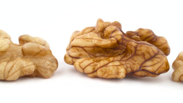 Row of walnuts without the shell are moving horizontally from one side of the frame to other. Isolated on the white background. Close-up. Macro.