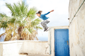 Frau macht einen Parkour Sprung in einem Dorf in Santorin 