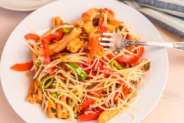 Italian food - Pasta with red pepper and parmesan on a white plate close-up
