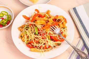 Italian food - Pasta with red pepper and parmesan on a white plate on a rustic light table, top view