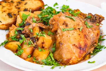Healthy rustic food - stew chicken with potatoes in tomato sauce on a white plate, close-up