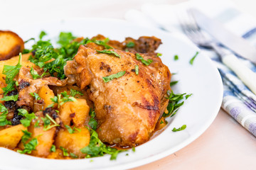 Healthy rustic food - stew chicken with potatoes in tomato sauce on a white plate, close-up
