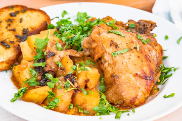 Healthy rustic food - stew chicken with potatoes in tomato sauce on a white plate, close-up