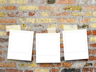 Three blank square instant photo frames on old weathered brick wall background
