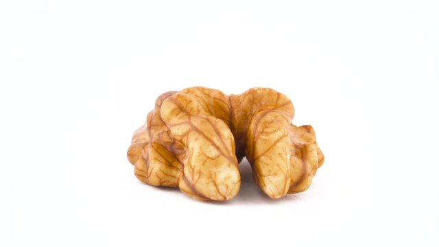 Macro shooting of single walnut without the shell. Slowly rotating on the turntable isolated on the white background. Close up.