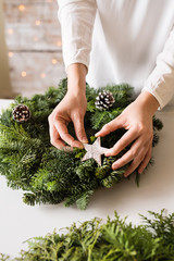 A unrecognizable woman decorating a christmas wreath.
