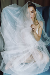 Portrait of stunning blonde bride with deep eyes hidden under blue veil
