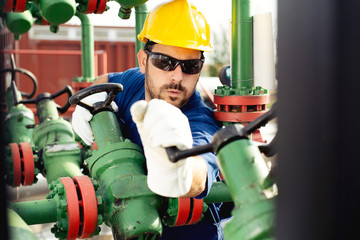 Oil worker turning valve on oil rig