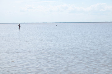 Fototapeta na wymiar Running children on the surface of lake at summer. Salt shallow lake in Russia. Loneliness concept in big world