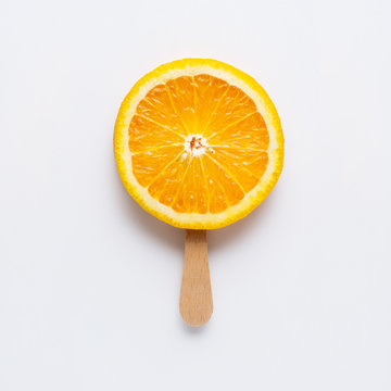 Natural and cold / Creative concept photo of orange slice arranged as ice cream popsicle on grey background.