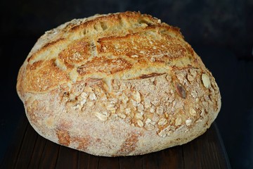 Fresh homemade bread from whole wheat and rye flour with flax seeds, pumpkin and oat flakes on a brown background. Crisp. French bread.  Bread at leaven. Unleavened bread. Lunch time