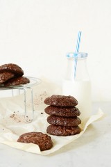 Round baked chocolate biscuits and a bottle of milk on a light background. Chocolate Brownie