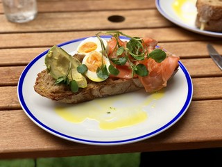 Smoked salmon, soft boiled egg and avocado on sourdough toast with watercress and police oil dressing