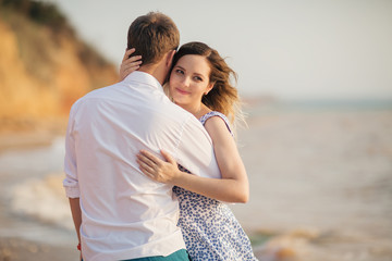 Cute couple hugging on the beach. Young family nestles outdoors. Woman forgives a man.