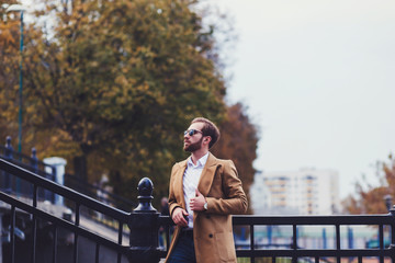 Portrait of young handsome stylish man in elegant coat. Outdoor fashion autumn portrait