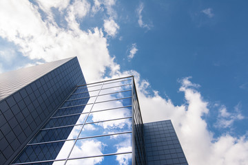 EDIFICIO MODERNO REFLEJA DIA SOLEADO Y NUBES