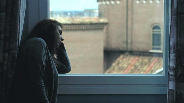 depressed beautiful woman at the window. sadness, worries, problems