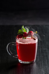 Autumn and winter hot cocktail with cherries and cinnamon on a black background.