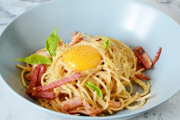 Pasta carbonara with bacon and parmesan in gray plates on the table, restaurant serve. Traditional Italian cuisine. Home family dinner.View from above