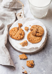 Healthy organic oat cookies with chocolate with glass of milk on wooden board on stone kitchen table background.