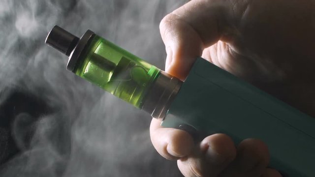 Vape device - RDA and mech mod in male hand with large amount of vapour clouds or steam