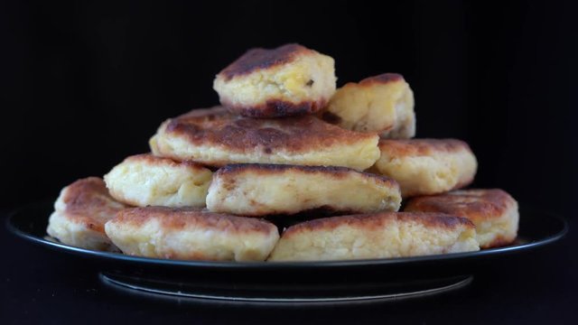 Potato cakes, ukrainian name potato zrazy, stuffed mushrooms or meat or cheese with herbs cream are fried in vegetable oil on black background, close up, rotates. Traditional Ukrainian cuisine