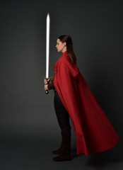  full length portrait of brunette girl wearing red medieval costume and cloak. standing pose ...