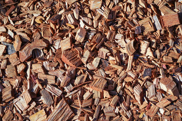 A pile of wood sawdust lies on the ground in sunny weather. 