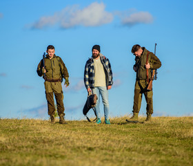 Hunters with guns walk sunny fall day. Hunting as hobby and leisure. Brutal hobby. Group men hunters or gamekeepers nature background blue sky. Guys gathered for hunting. Men carry hunting rifles