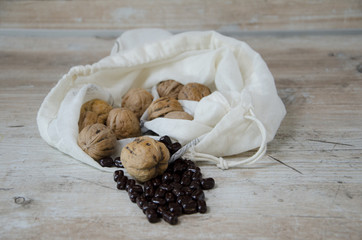 Walnuts with chocolate beans in a linnen bag, the bag is laying on a kitchen table.