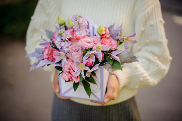Girl holding a box of tender pink and violet flowers