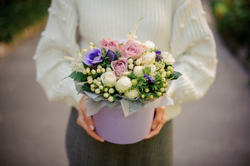 Girl holding a box of tender white, blue and violet flowers