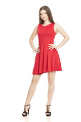 Young woman in short red dress and high heels on white background