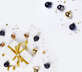 Fototapeta premium Christmas flat lay scene with golden, gray and black glass balls and gift box with copy space on white background