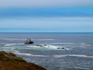 Obraz premium Fishing boat near rocks at the sea