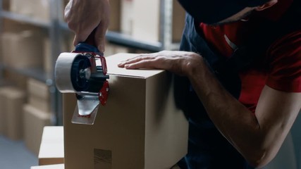 Warehouse Worker Checks and Seals Cardboard Box Ready for Order Shipment.
