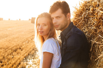 Amazing young loving couple standing on the field posing.