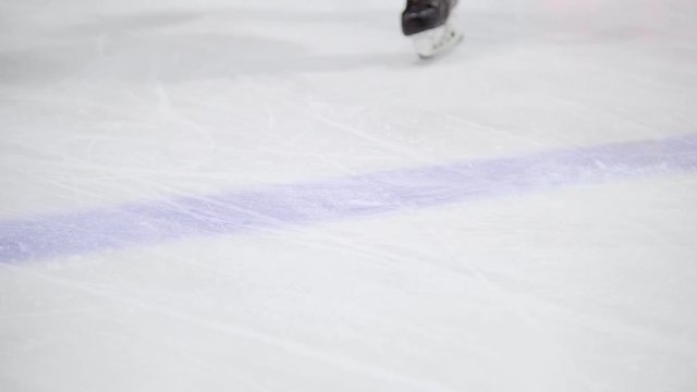 Hockey players drive through a hockey field with a black puck. View of legs